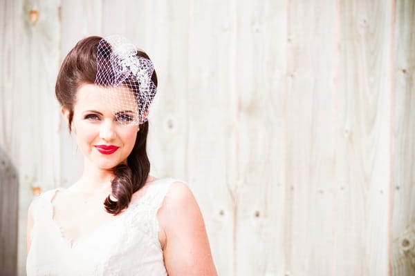 Vintage bride with birdcage veil in front of white fence