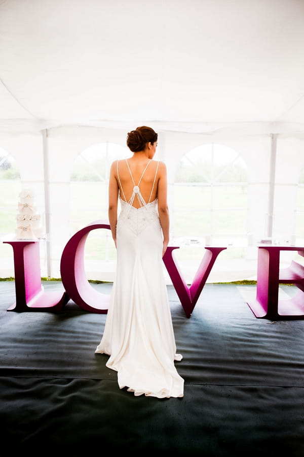 Bride standing in front of large purple LOVE letters