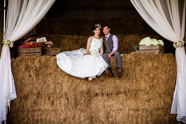 Vintage bride and groom sitting on hay bales