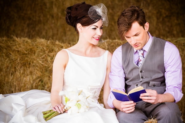 Bride and groom on hay bales reading a book