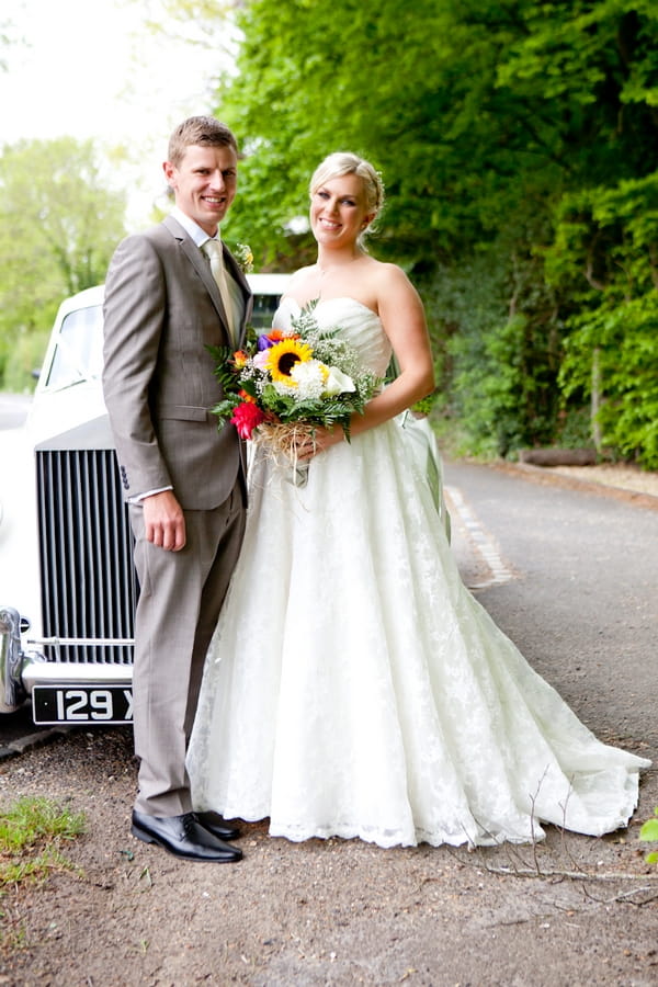 Bride and groom in front of wedding car