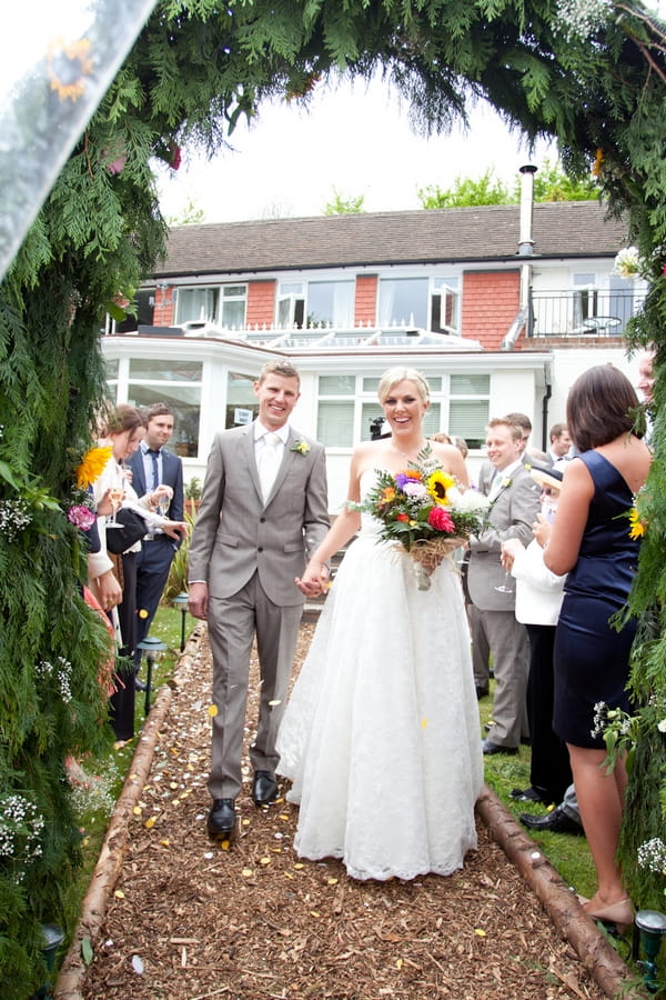 Bride and groom walking under arch