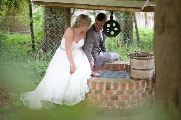 Bride and groom sitting on well