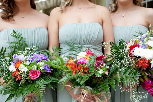 Bridesmaids in green dresses holding bouquets