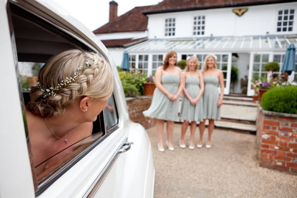 Bride looking out of window of wedding car at bridesmaids