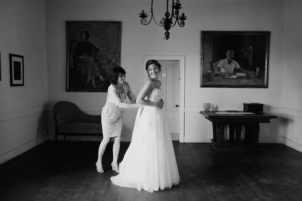 Bride having back of wedding dress done up