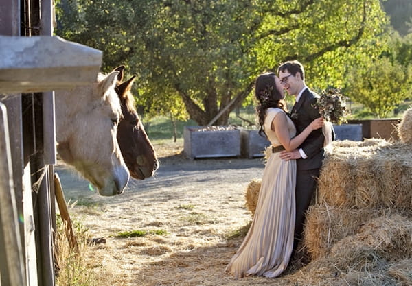 Bride and groom leaning on hay bales