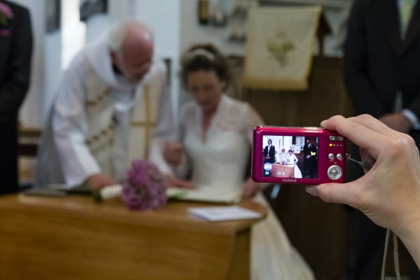 Someone taking picture of bride signing the register