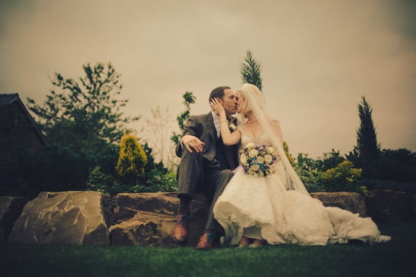 Bride and groom kissing on fallen tree