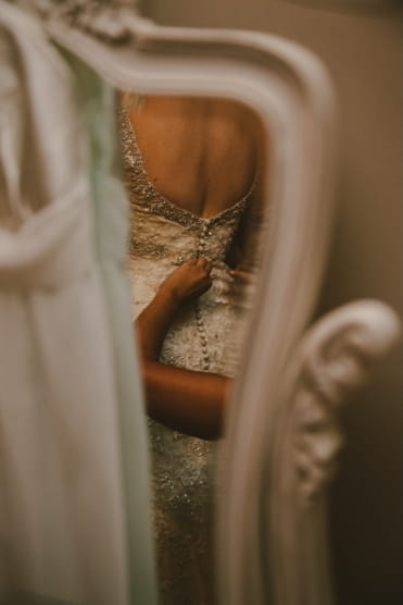 Reflection of bride having back of dress done up