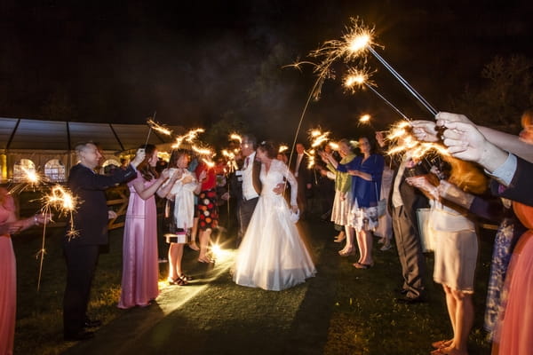 Bride and groom walking through guests with sparklers