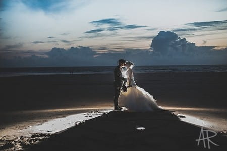 Bride and groom on beach with light shining behind them - Picture by Ayesha Rahman Photography