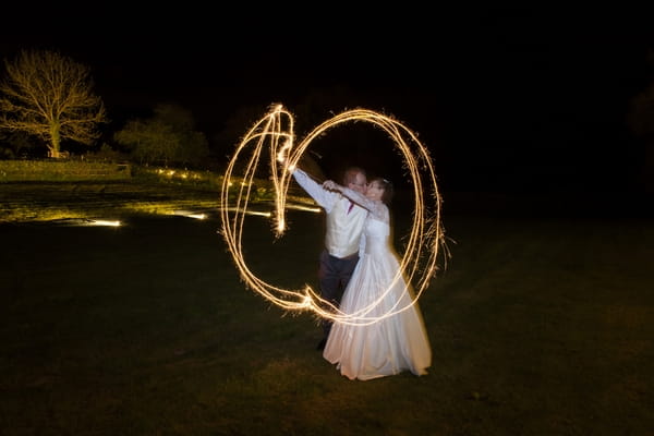 Bride and groom making shapes with sparklers