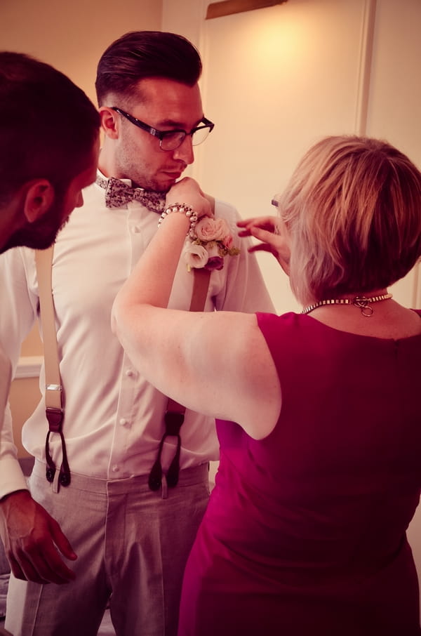 Lady putting on groom's buttonhole