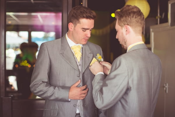 Best man helping groom with buttonhole