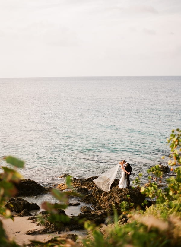 Bride and groom on rocks by sea