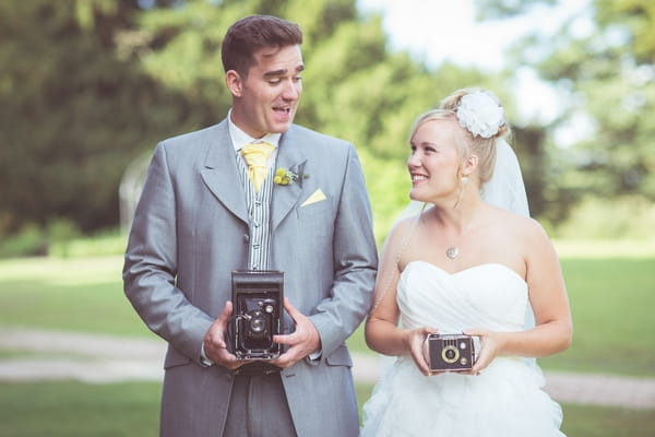 Bride and groom holding vintage cameras