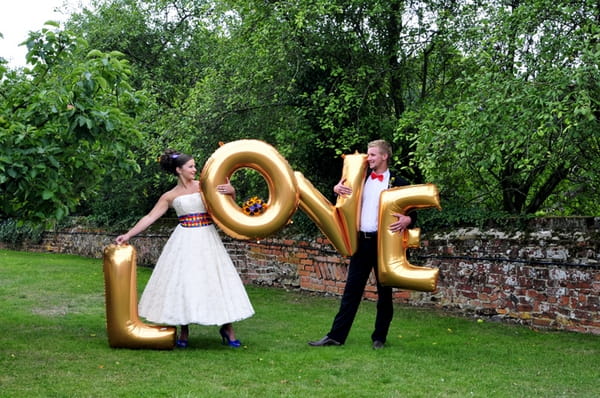 Bride and groom carrying gold love letters