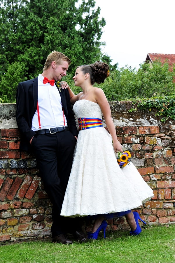 Bride and groom standing by wall