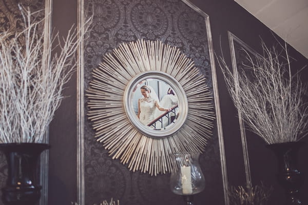 Reflection in mirror of bride walking down stairs