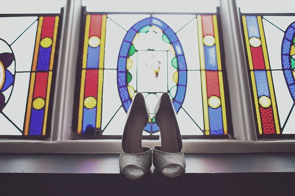 Wedding shoes in front of stained glass window