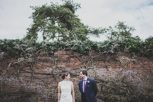 Bride and groom standing in front of wall