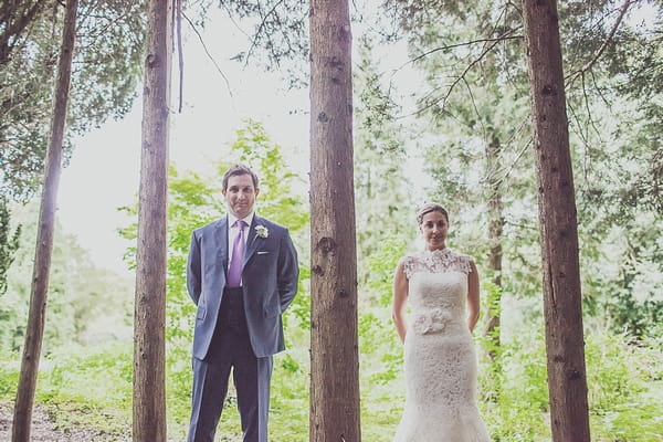 Bride and groom standing amongst trees