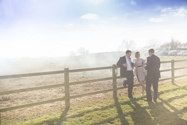 Wedding guests leaning on fence