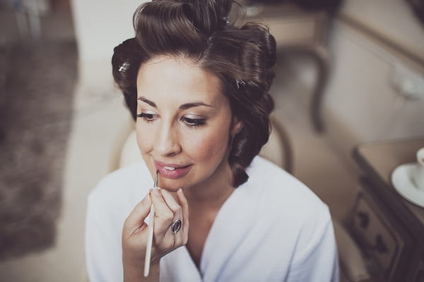 Bride having lip gloss applied