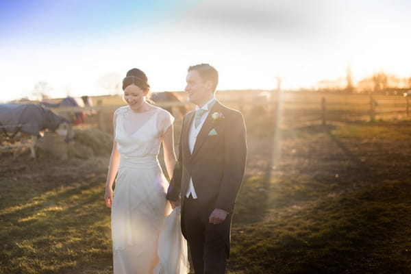 Bride and groom walking across field