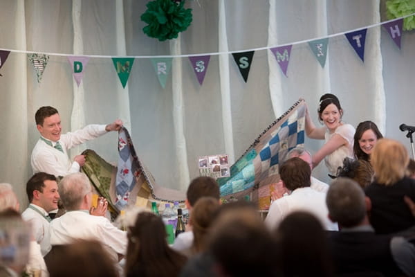 Bride and groom holding up large piece of material