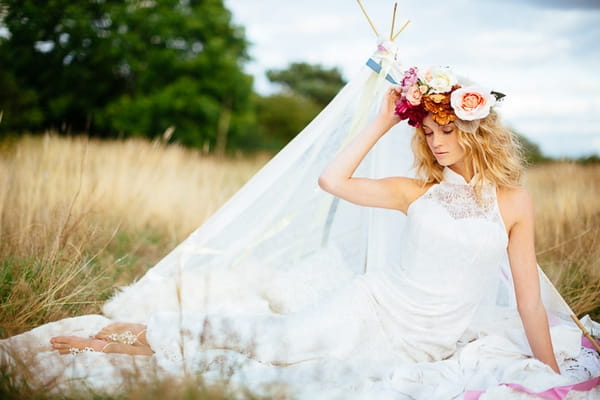 Boho bride laying in front of small tipi