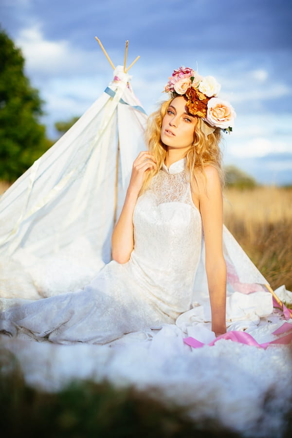 Boho bride with flower crown in front of tipi