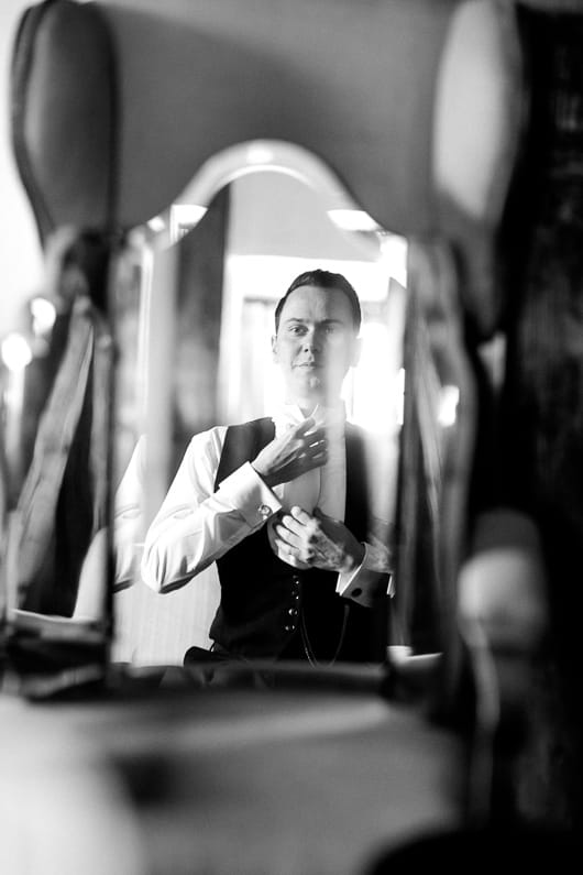 Groom adjusting cravat in mirror