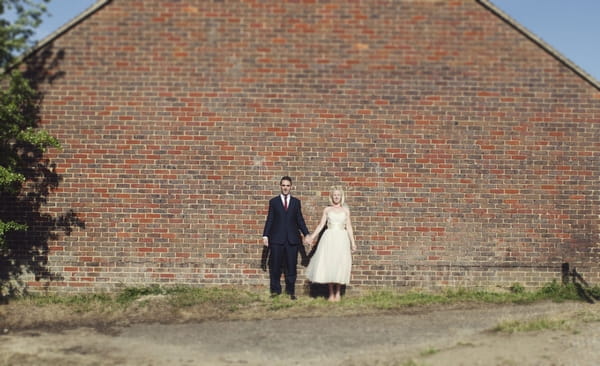 Bride and groom standing by wall