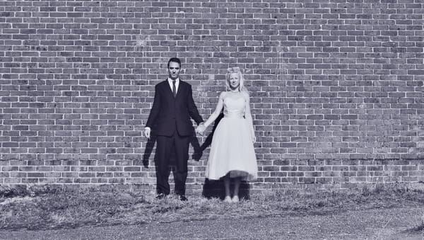 Bride and groom standing by wall