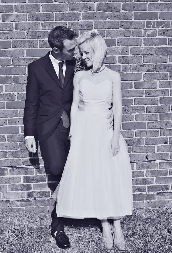 Bride and groom standing by wall