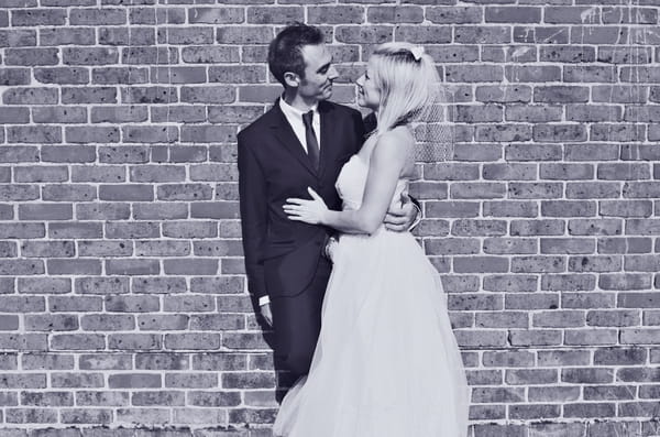 Bride and groom standing by wall