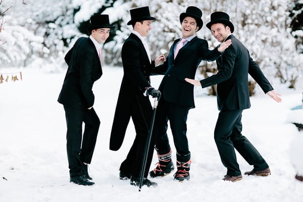 Groomsmen with top hats in snow