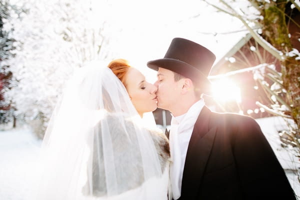 Bride and groom kiss in snow