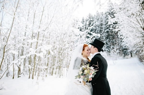 Groom kissing bride in snow