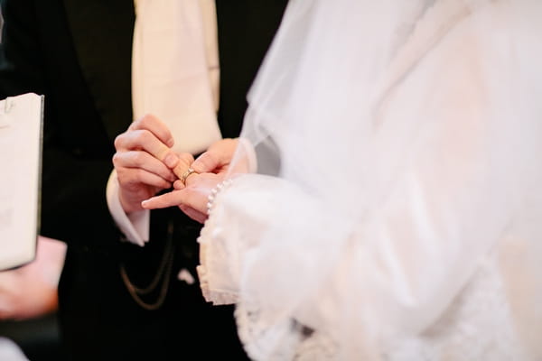 Groom putting ring on bride's finger