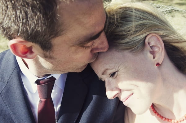 Groom kissing bride on the head