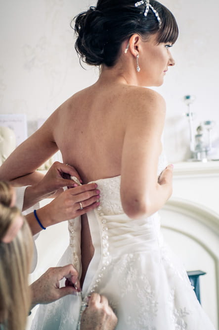 Bride having wedding dress done up