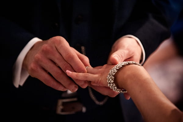 Groom putting ring on bride's finger