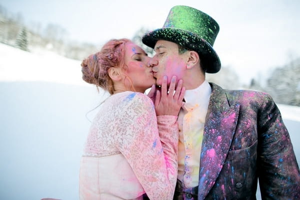 Bride and groom kiss covered in holi powder in the snow