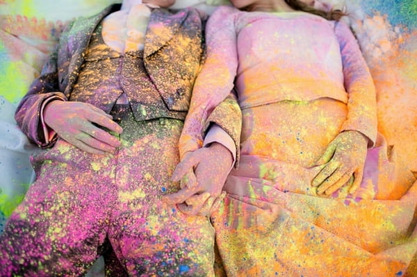 Bride and groom covered in holi powder laying in the snow