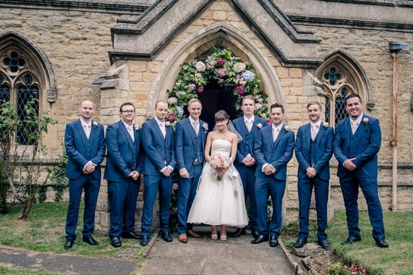 Bride and groomsmen standing at entrance to church