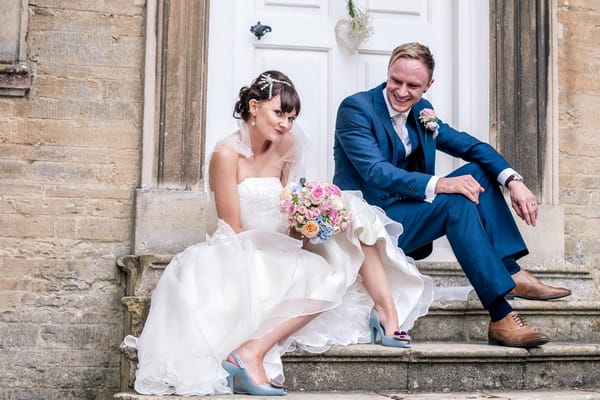 Bride and groom sitting on steps of Hinwick House