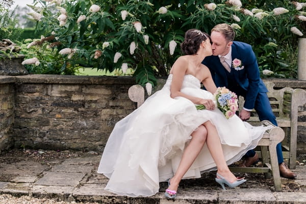 Bride and groom kissing on bench